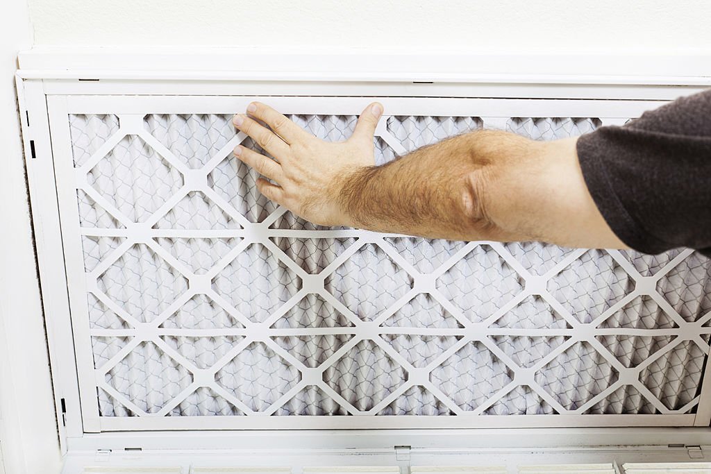 Man replacing A/C filter for a home air conditioning system.