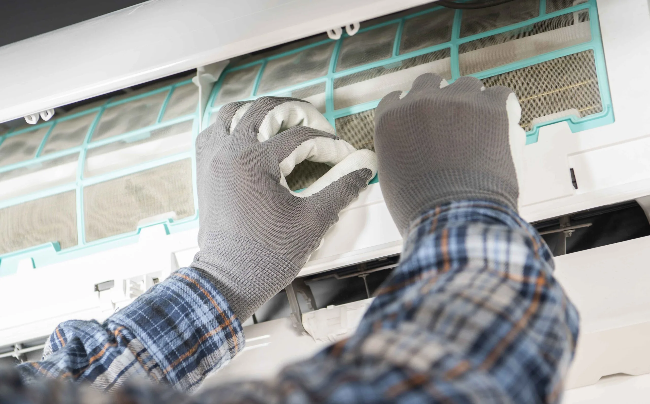 technician wearing gloves cleaning HVAC filter in lees summit home