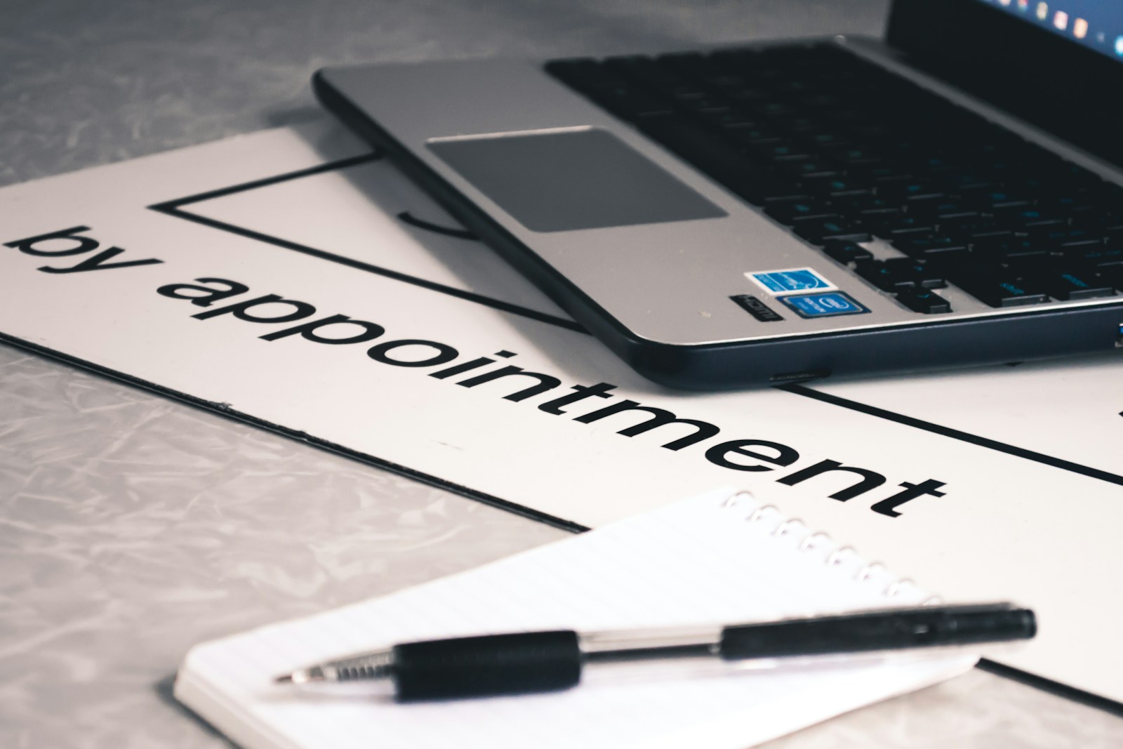 Notebook and laptop next to sign reading 'by appointment'