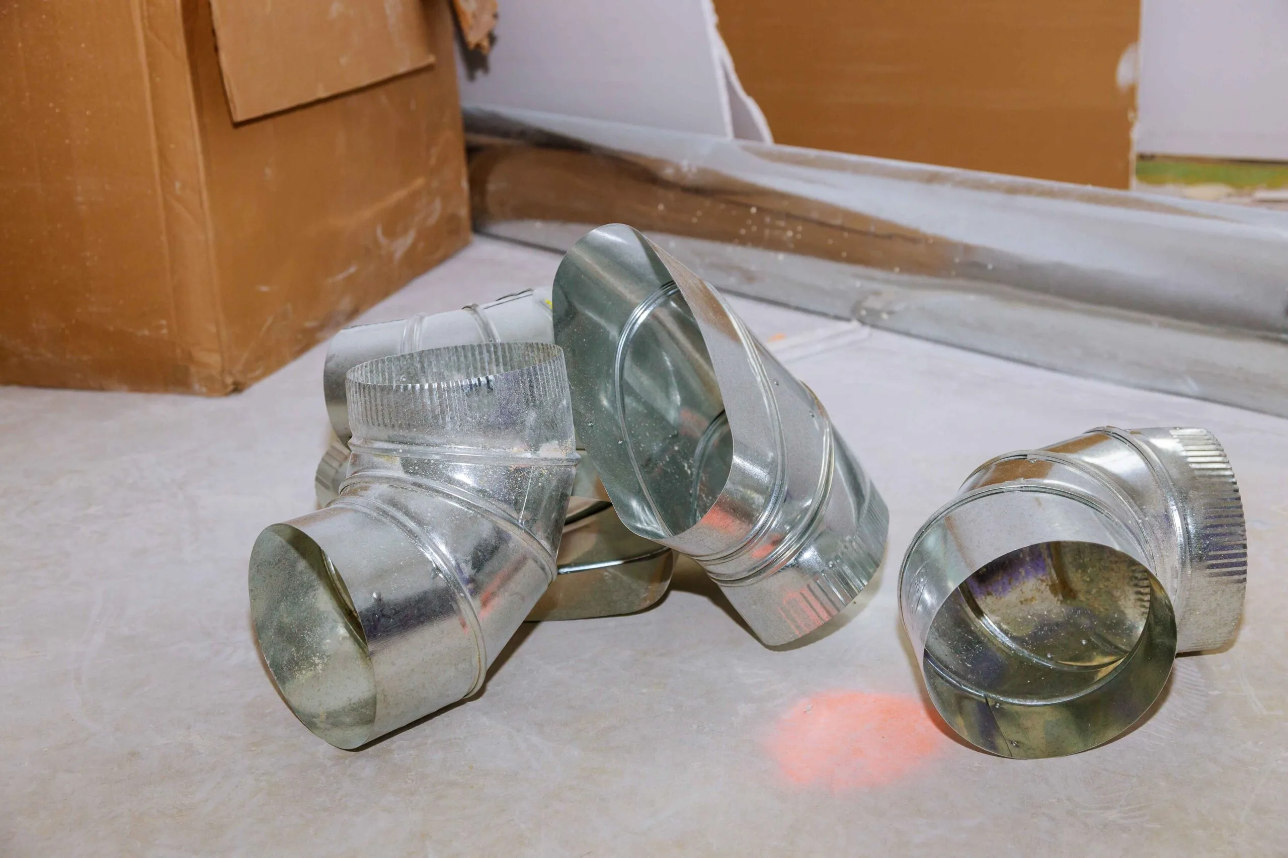 metal HVAC duct fittings on the floor during air duct maintenance in lees summit