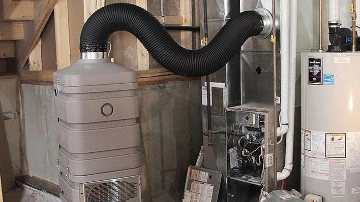 HVAC system with attached vacuum hose during air duct cleaning in Kansas City basement.