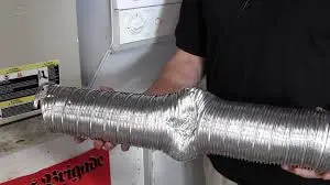 technician holding bent dryer vent hose in kansas city laundry area