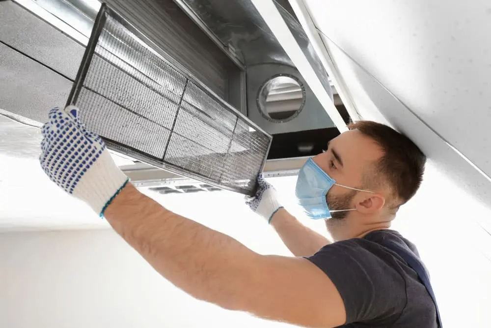 technician cleaning air duct vent in kansas city residential living room
